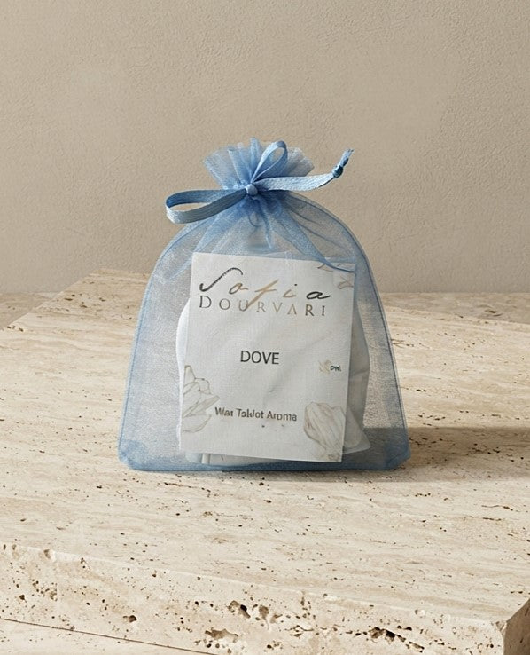 Sofia Dourvari Dove Wax Tablet Aroma in a tied sky blue organza bag with branded label, on a travertine stone surface