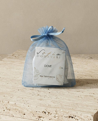 Sofia Dourvari Dove Wax Tablet Aroma in a tied sky blue organza bag with branded label, on a travertine stone surface