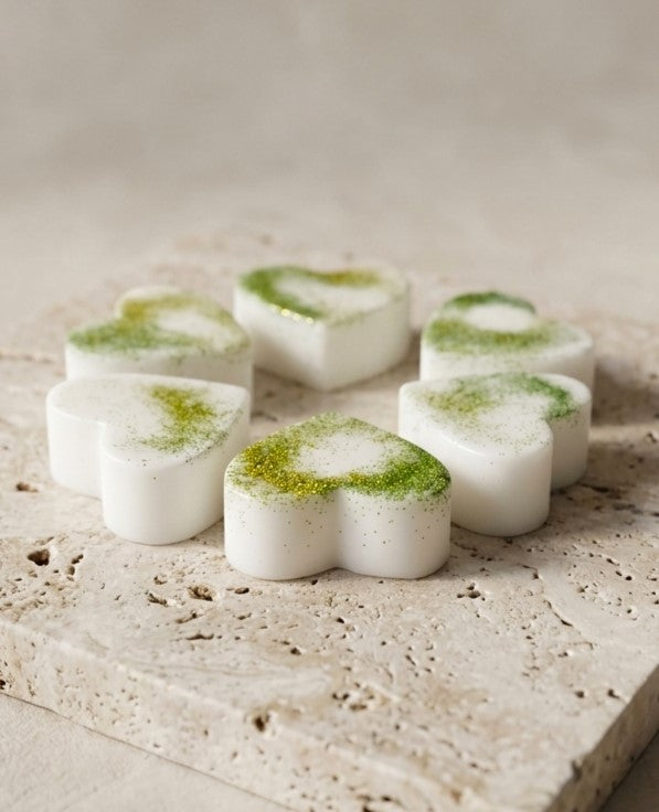 Sofia Dourvari Earl Grey & Bergamot heart-shaped coconut wax melts with green botanical detailing, arranged on a travertine stone tile