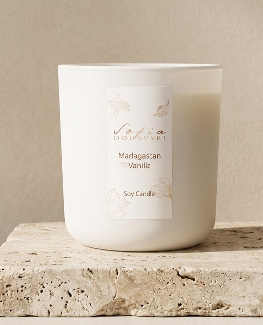 Sofia Dourvari Madagascan Vanilla heart-shaped coconut wax melts with gold shimmer detailing, arranged in a circle on a travertine stone surface