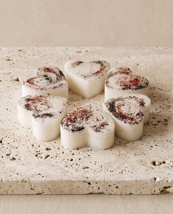 Sofia Dourvari Black Pepper heart-shaped coconut wax melts with dark spice swirl detailing, arranged on a travertine stone tile