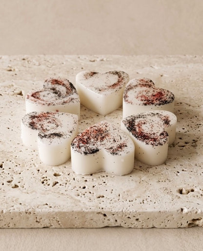 Sofia Dourvari Black Pepper heart-shaped coconut wax melts with dark spice swirl detailing, arranged on a travertine stone tile