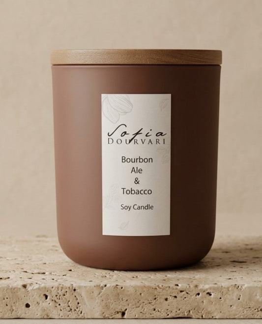 ofia Dourvari Bourbon Ale & Tobacco soy scented candle in a rich terracotta matte vessel with wooden lid, on a stone surface